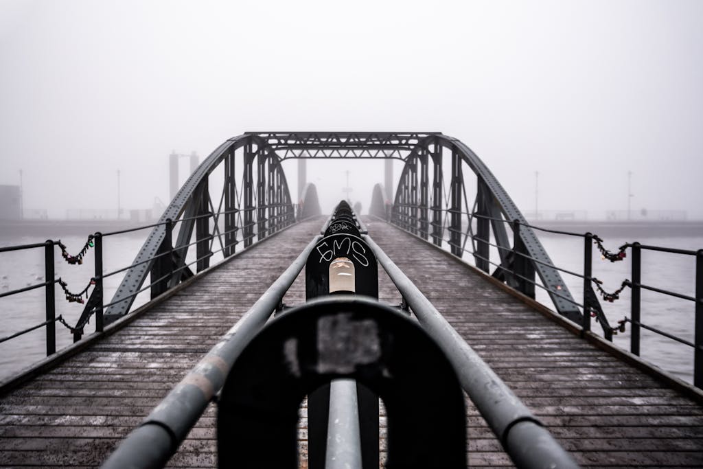 Moody image of a steel bridge in fog, emphasizing symmetry and structure.